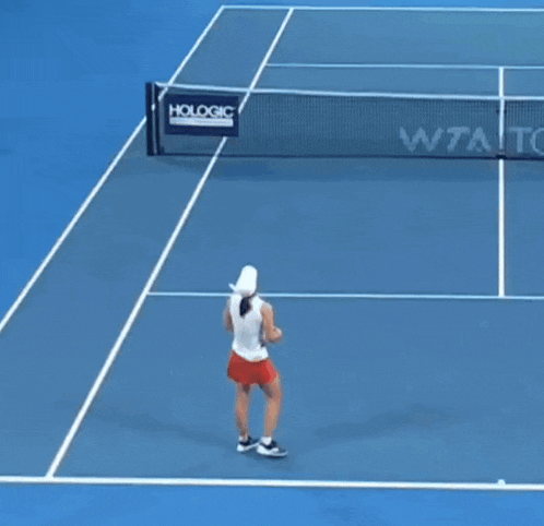 a woman is holding a tennis racquet on a tennis court with a sign that says hologic