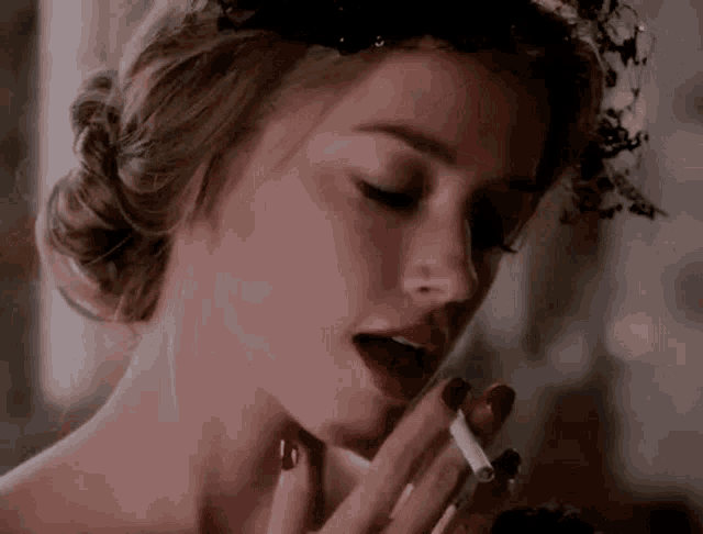 a woman is smoking a cigarette and wearing a black headband .