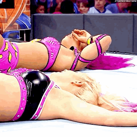 two female wrestlers are laying on the floor with their heads on their knees ..