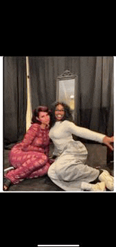 two women are posing for a picture together in a bedroom .