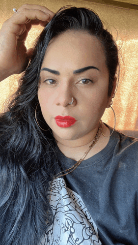 a woman with red lipstick and a nose ring is wearing a versace t-shirt