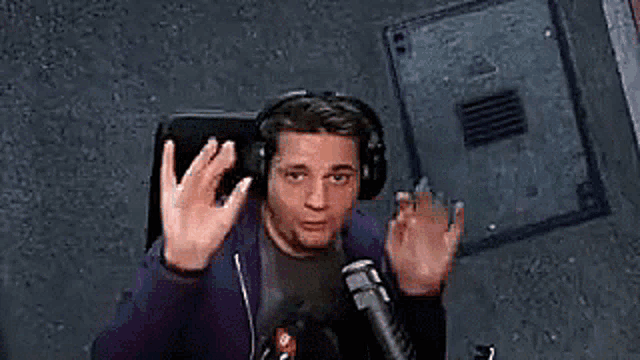 a man wearing headphones and a microphone is sitting in front of a microphone and making a funny face .