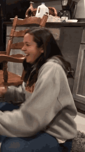 a woman wearing a sweatshirt that says ' ucsd ' on it sits in a chair