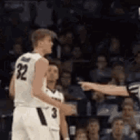 a basketball player with the number 32 on his jersey is pointing at the referee .