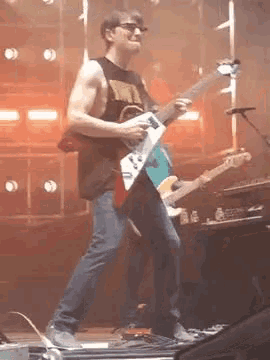 a man is playing a guitar on a stage while standing on a treadmill .