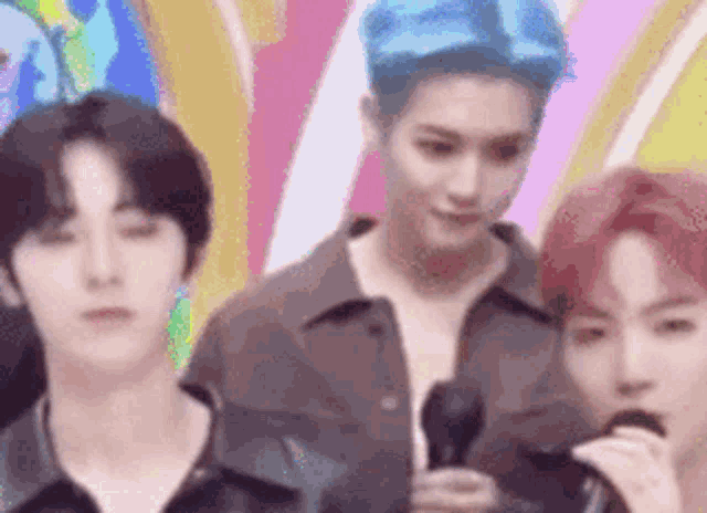 a group of young men are standing next to each other in front of a colorful background .
