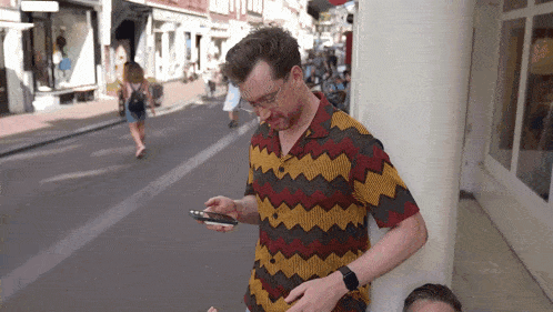a man wearing a colorful shirt is looking at his phone