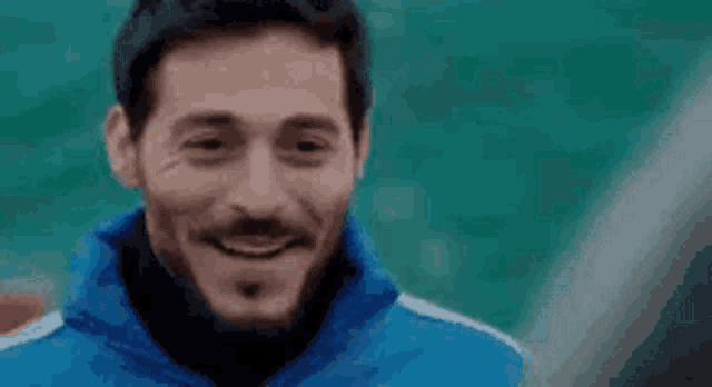 a man with a beard is smiling in a blue jacket .