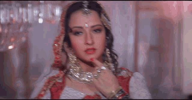 a woman is wearing a veil and jewelry and is looking at the camera .