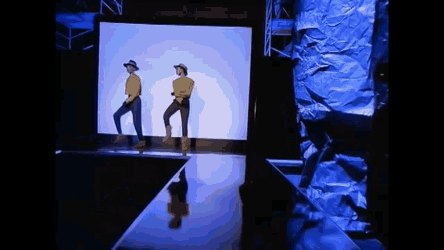 a couple of people are dancing on a stage in front of a large screen .