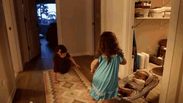 a girl in a blue dress is standing next to a baby in a stroller