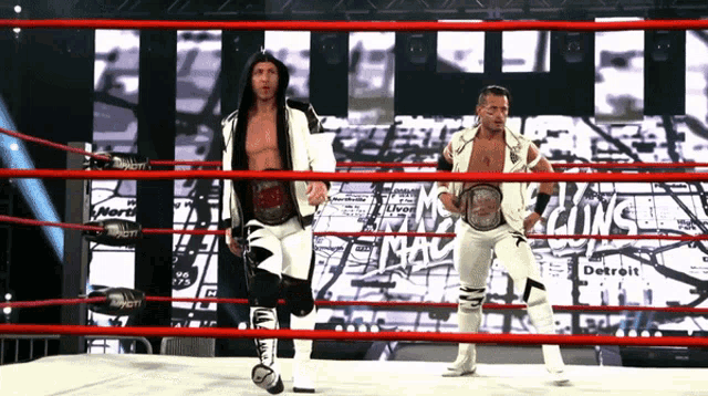 two wrestlers are standing in a ring with the word detroit in the background