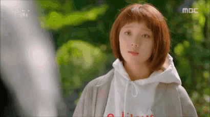 a woman with short red hair is wearing a white hoodie and looking at the camera .