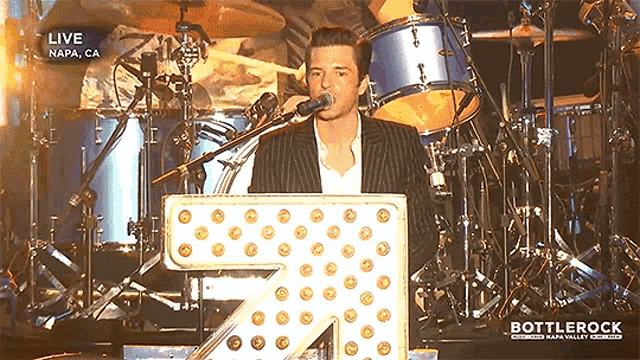 a man singing into a microphone in front of a sign that says live napa ca
