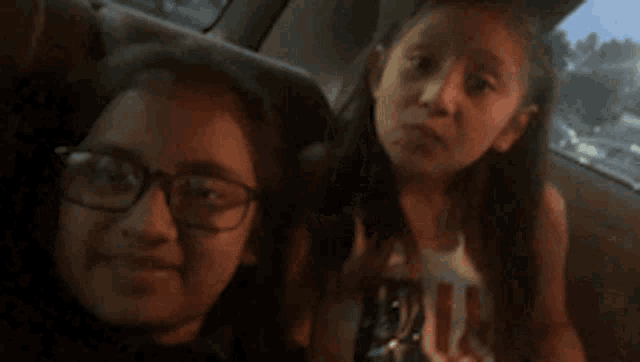 a woman and a little girl are sitting in the back seat of a car