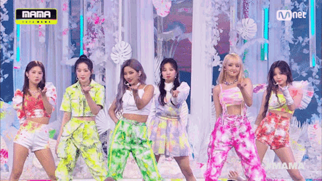 a group of girls are standing on a stage with a mnet banner above them