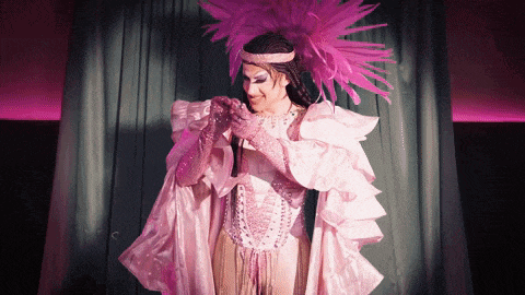 a woman in a pink and white costume with a feathered headpiece