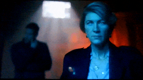 a woman in a blue jacket stands in front of a man