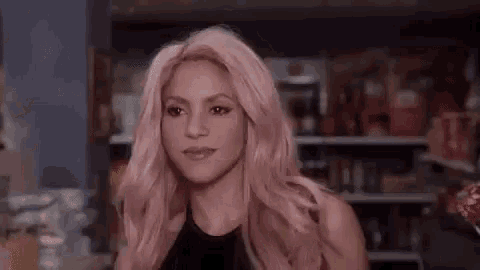 a woman with pink hair and a black top is standing in a store .