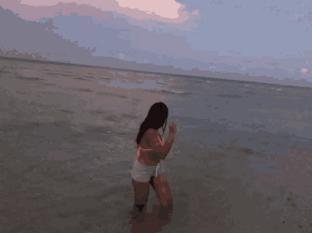 a woman in a pink bikini is standing in the ocean