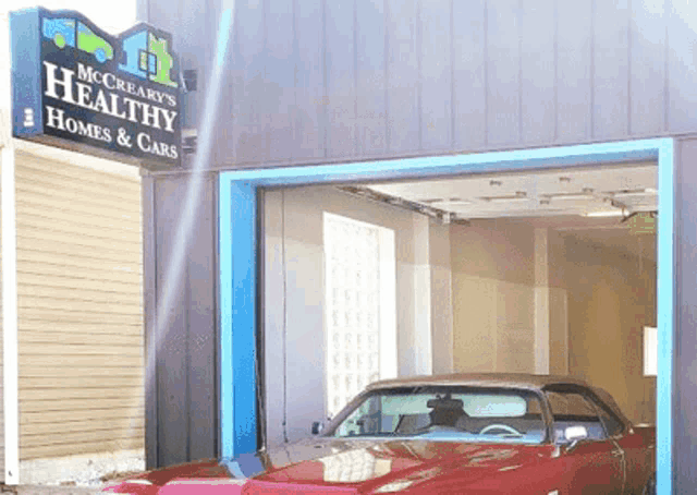 a red car is parked in front of a building that says mccreary 's healthy homes and cars