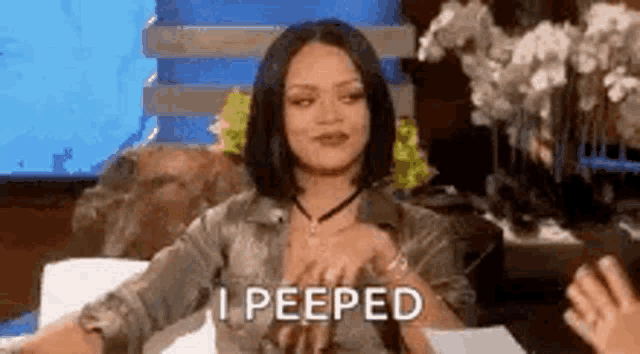a woman is sitting at a table with her hands on her chest and the words `` i peeped '' written next to her .