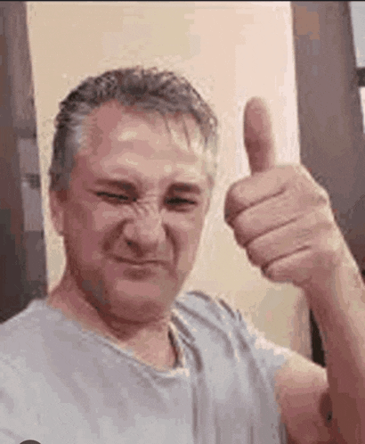 a man is making a face and giving a thumbs up .