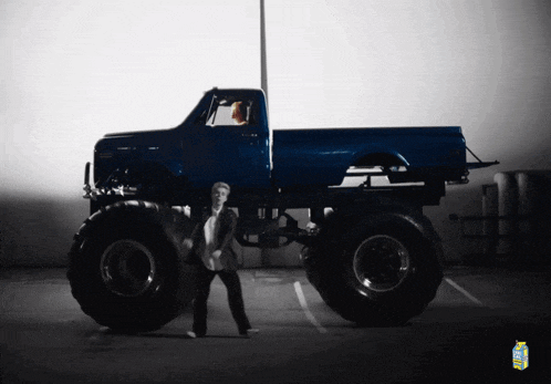 a man in a suit is standing in front of a monster truck