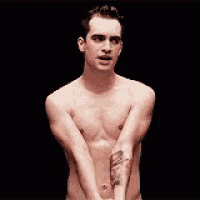a shirtless man is standing on a stage with his hands folded in front of him .