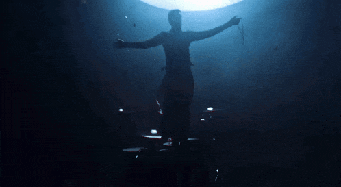 a silhouette of a man with his arms outstretched in front of a light .