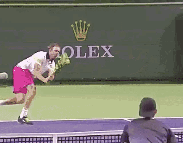 a man is playing tennis in front of a rolex logo