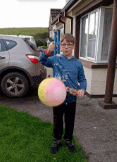 a boy is holding a balloon in front of a car