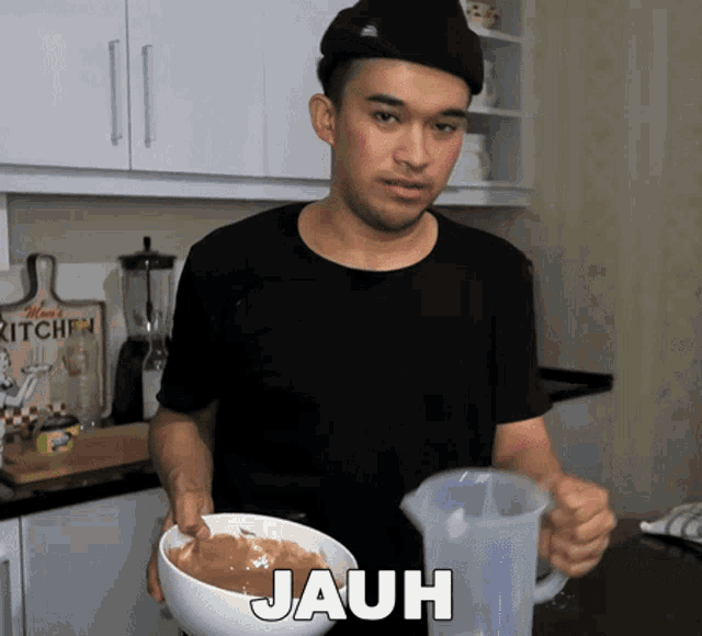 a man in a black shirt is holding a bowl of food and a pitcher of water with the word jauh written on it