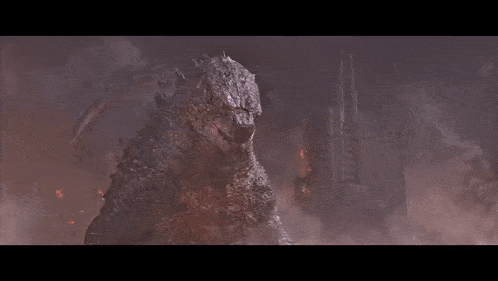a giant monster is standing next to a smaller monster in a foggy area .