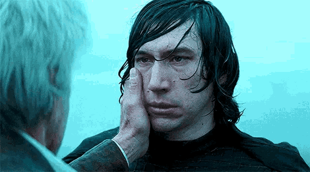 a man is touching another man 's face in a scene from star wars : the force awakens .