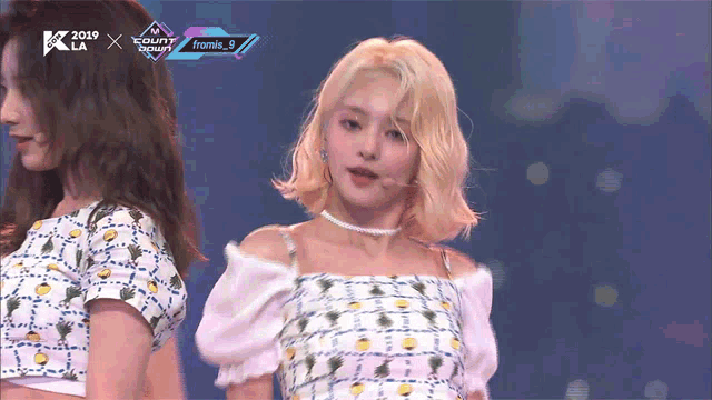 a woman with blonde hair is standing in front of a screen that says 2019