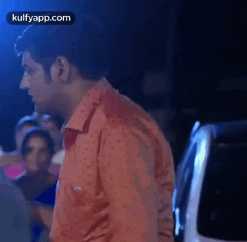 a man in a red shirt is standing in front of a crowd .