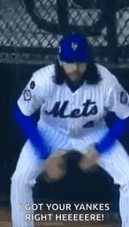 a baseball player in a mets uniform is kneeling down and holding a baseball in his hands .