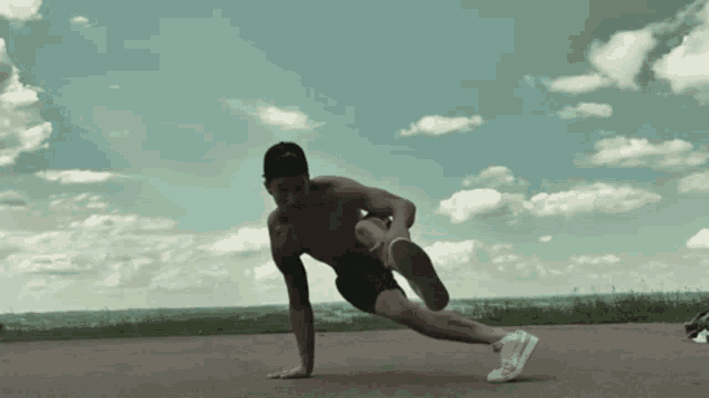 a shirtless man is doing push ups on a road