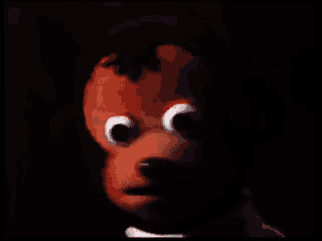 a close up of a stuffed doll with big eyes