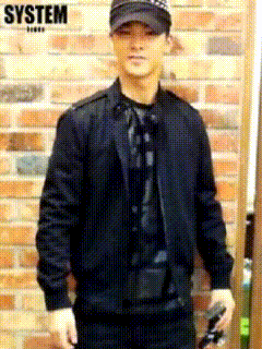 a man standing in front of a brick wall with the word system on the bottom right