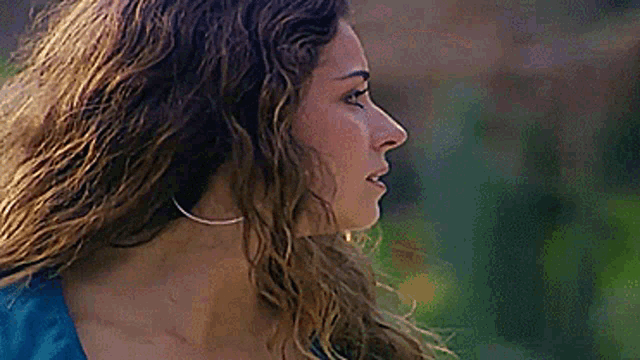 a close up of a woman 's face with long curly hair and earrings .