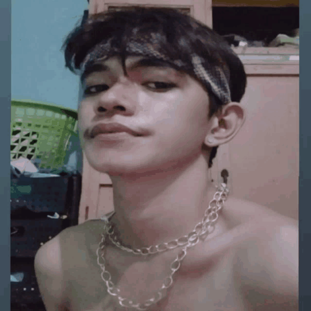 a shirtless young man wearing a necklace and a bandana