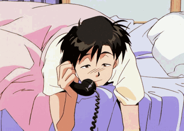 a man is laying on a bed talking on a telephone