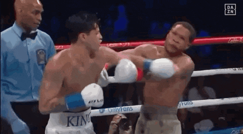 two men are fighting in a boxing ring with a referee watching .