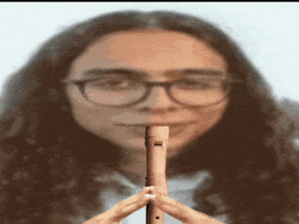 a woman wearing glasses is playing a flute in a blurry photo .