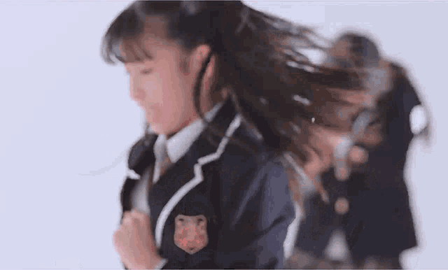 a girl in a school uniform is dancing in front of a white background .