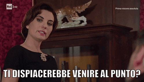 a woman in a black dress is talking to a man with the words ti dispiacerebbe venire al punto