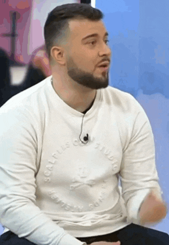 a man with a beard is wearing a white sweater that says sculptus on it