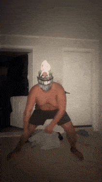 a shirtless man wearing a mask and glasses is dancing in a dark room